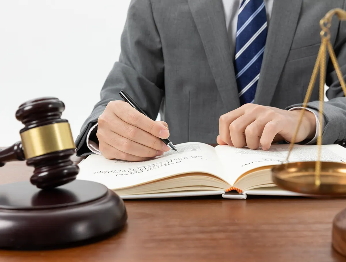 closeup-shot-person-writing-book-with-gavel-table-img