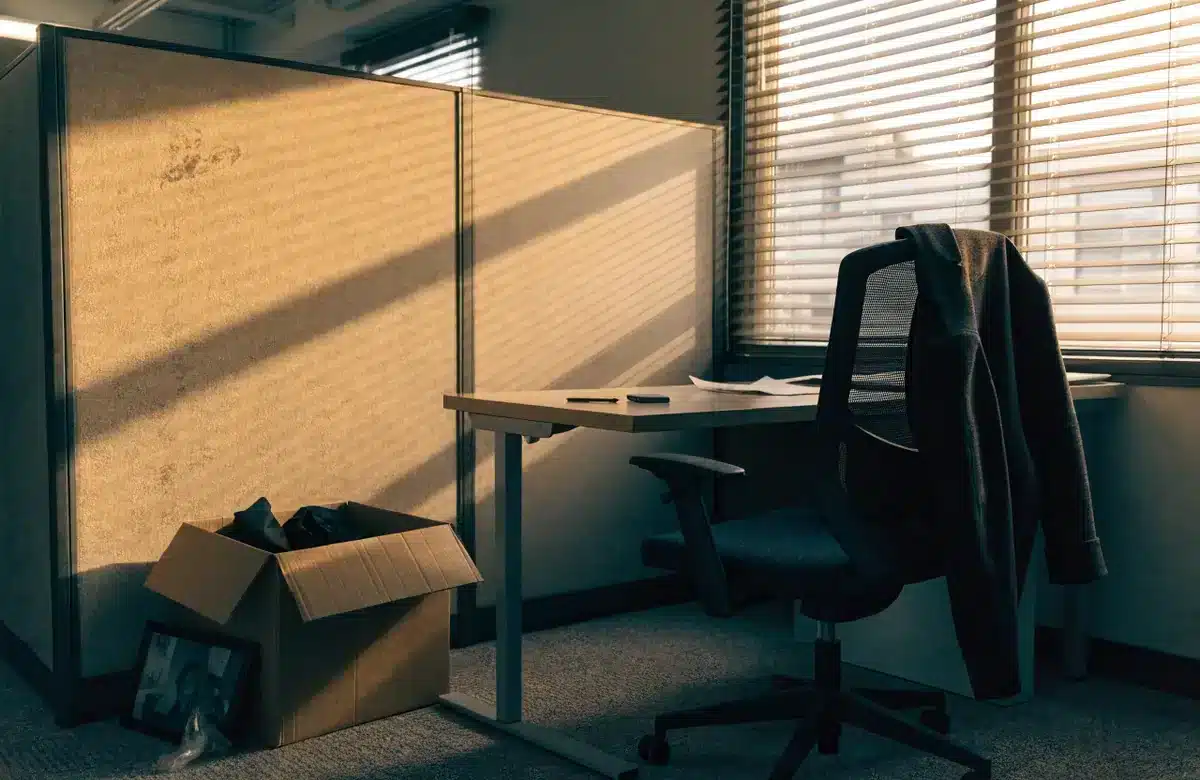 Empty office cubicle with packed personal items after a job loss